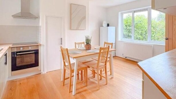 Une cuisine moderne avec une table à manger, des chaises et un four encastré.