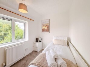 A bedroom with a bed, a bedside table, a lamp, a window, and a radiator. - Blue Boar Lane (Norwich)