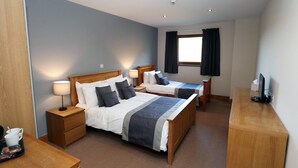A hotel room with two beds, a desk, and a TV. - Afan Mountain Lodge (Port Talbot)