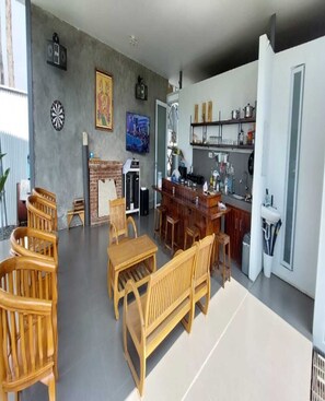 A spacious living area with a wooden dining set, a fireplace, and a kitchen area with a bar. - Cozzy Villa Nirwana Pangalengan (Pangalengan)