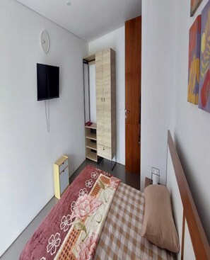 A bedroom with a bed, a TV, a wardrobe, and a door. - Cozzy Villa Nirwana Pangalengan (Pangalengan)