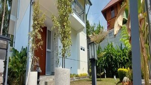 Ein modernes, zweistöckiges Gebäude mit Balkon, Betonpflanzgefäß und einer Straßenlaterne.