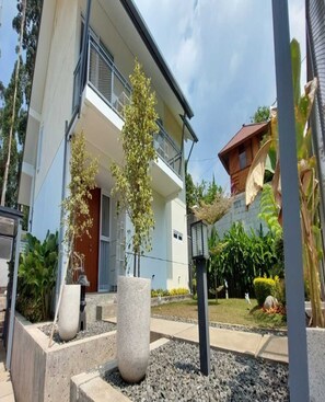 A modern two-story building with a balcony, a concrete planter, and a street lamp. - Cozzy Villa Nirwana Pangalengan (Pangalengan)