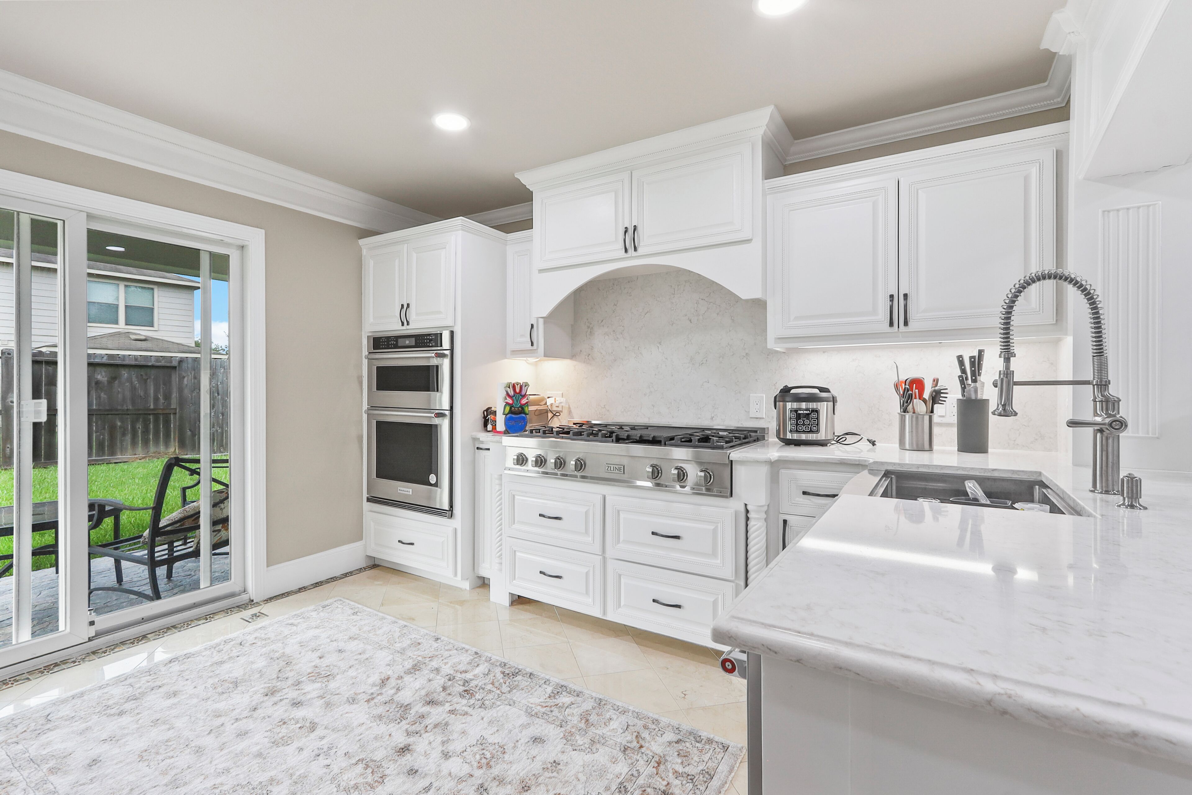 Una cocina moderna con muebles blancos, estufa a gas, horno y un lavaplatos empotrado.