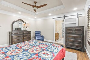 Un dormitorio con cama, cómoda, silla y puerta corredera que da a un baño.