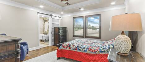 A bedroom with a bed, dresser, desk, and a ceiling fan.