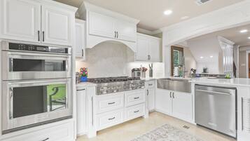 A modern kitchen with white cabinetry, stainless steel appliances, and a built-in dishwasher.