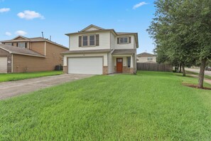 A two-story residential house with a garage, a front lawn, and a tree.