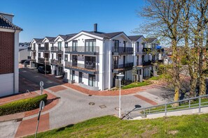 A modern residential building with multiple balconies, a paved driveway, and a clear sky. - Vrbo Property (Büsum)
