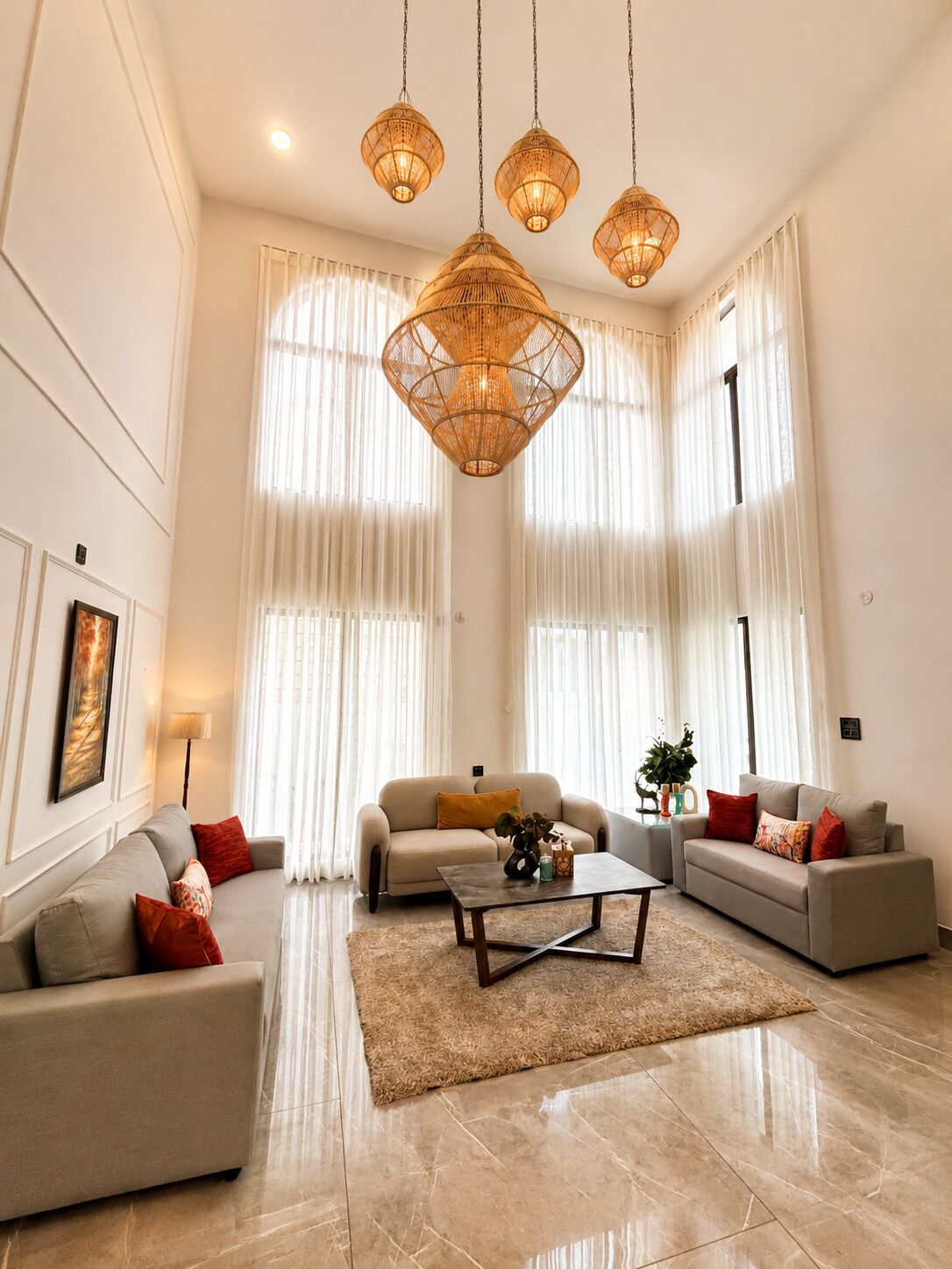 A spacious living room with a high ceiling, large windows, and a central coffee table.