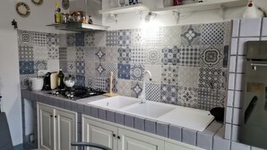 Uma cozinha com fogão a gás, duas pias e diversos azulejos estampados na parede.