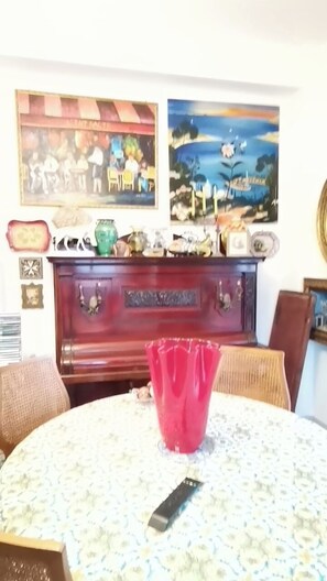 A room with a round table, a red vase, and a wooden cabinet with decorative items. - Splendida casa Taormina mare (Villagonia)