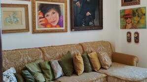 Uma sala de estar com um sofá grande, um candelabro e diversas obras de arte emolduradas na parede.