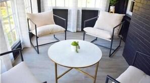 Een kamer met een ronde tafel, twee stoelen en een potplant.