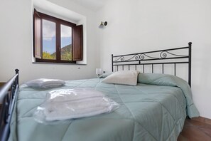 A single bed with a metal frame, a window with wooden shutters, and a view of greenery outside. - Fattoria San Pio - Cedro Room with Mountain View, Wi-Fi, Breakfast (Naso)