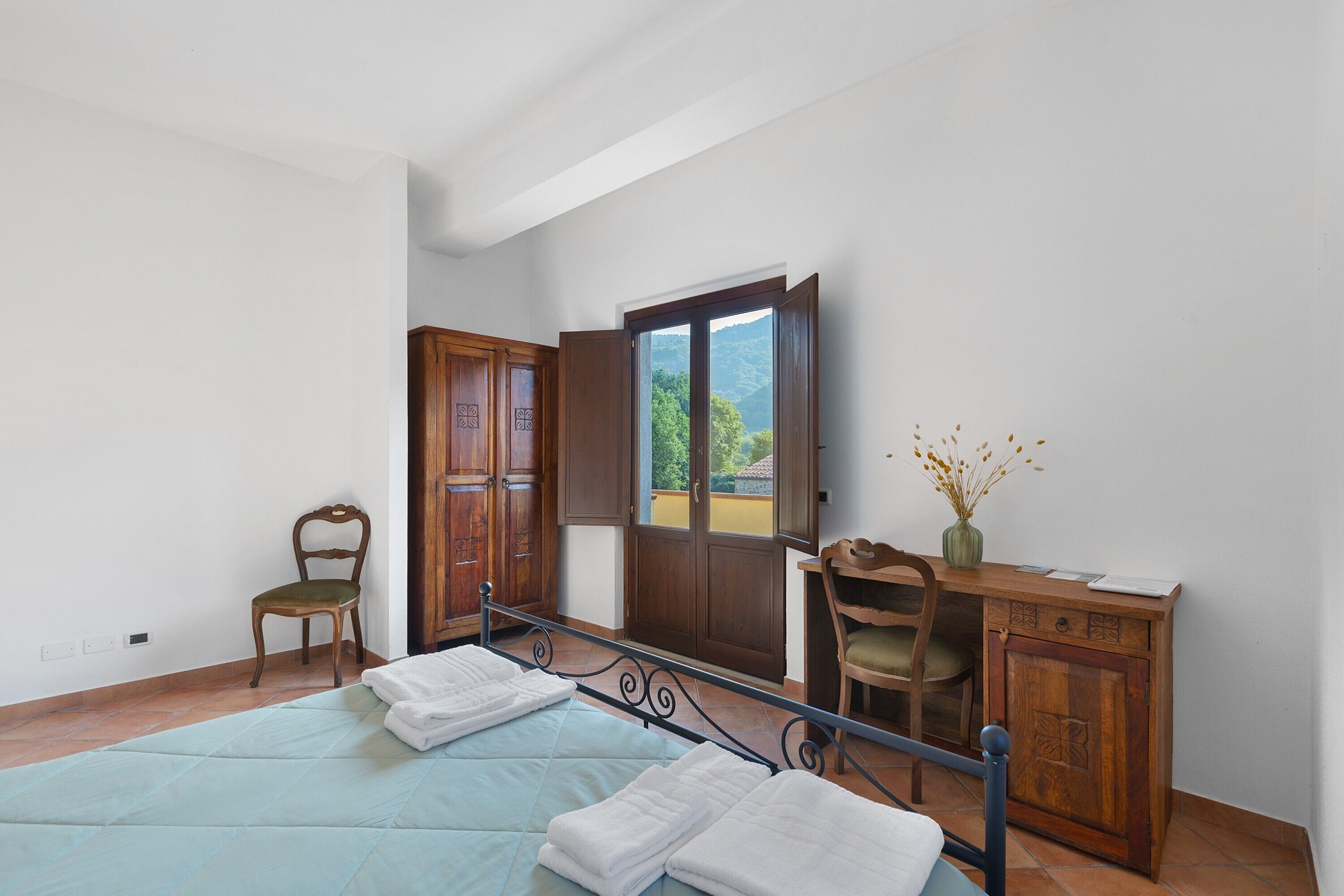 A bedroom with a bed, a chair, a desk, and a wardrobe.