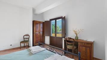 A bedroom with a bed, a chair, a desk, and a wardrobe.