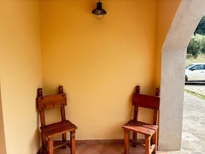 Two wooden chairs against a yellow wall with a light fixture above.