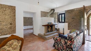 A room with a stone wall, a fireplace, a sofa, and a staircase.