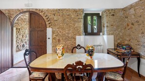 A dining area with a marble table, wooden chairs, and a decorative vase.