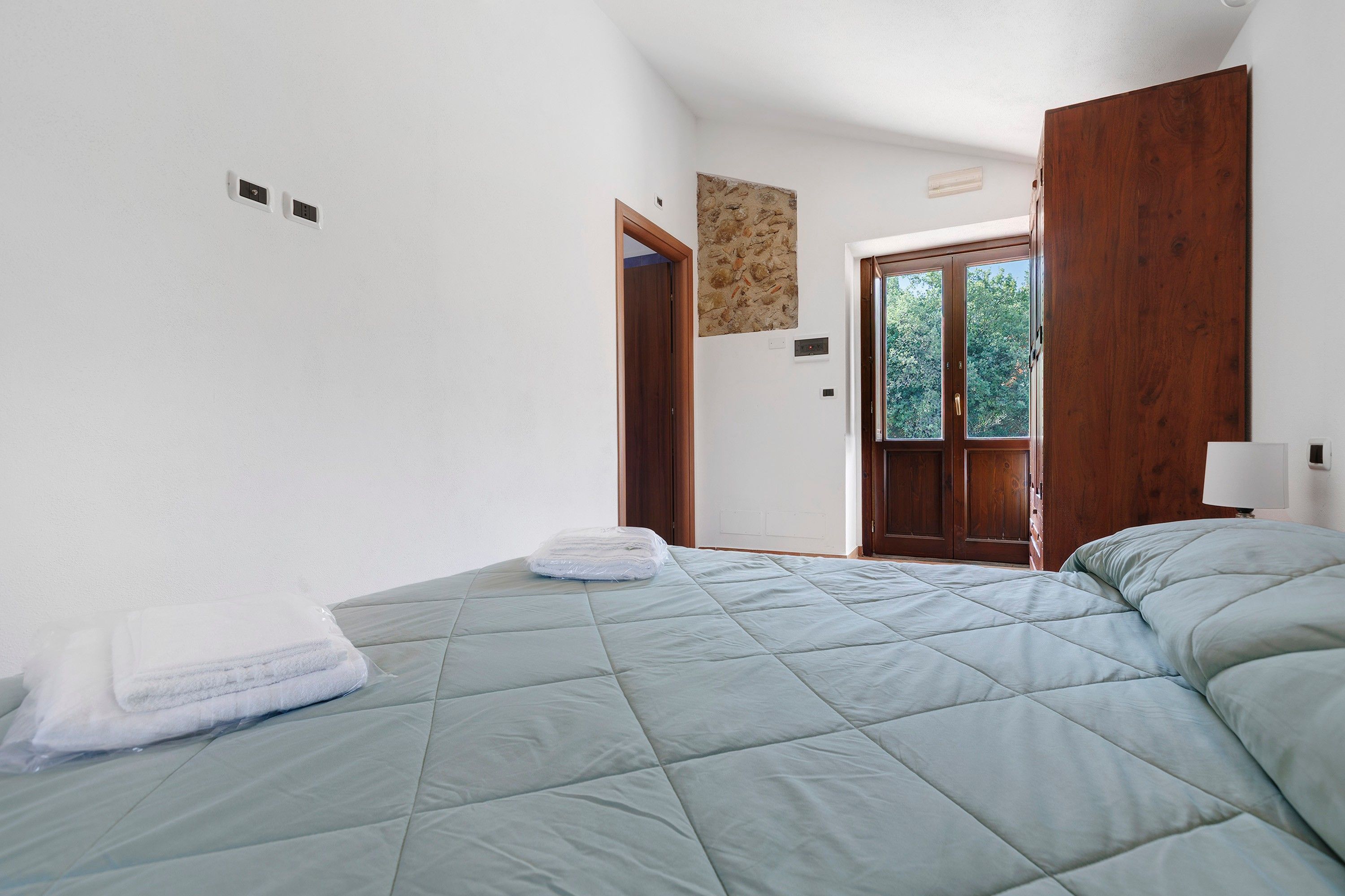 Un dormitorio con una cama, una puerta de madera y un ventanal.