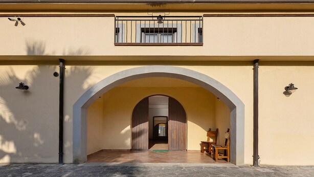 Ein Gebäude mit Bogenportal, einem Balkon mit Fenster und einer Tür zu einem Innenraum.
