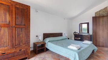 Une chambre à coucher avec une grande armoire en bois, un lit avec une couette, une table de chevet et une commode avec un miroir.