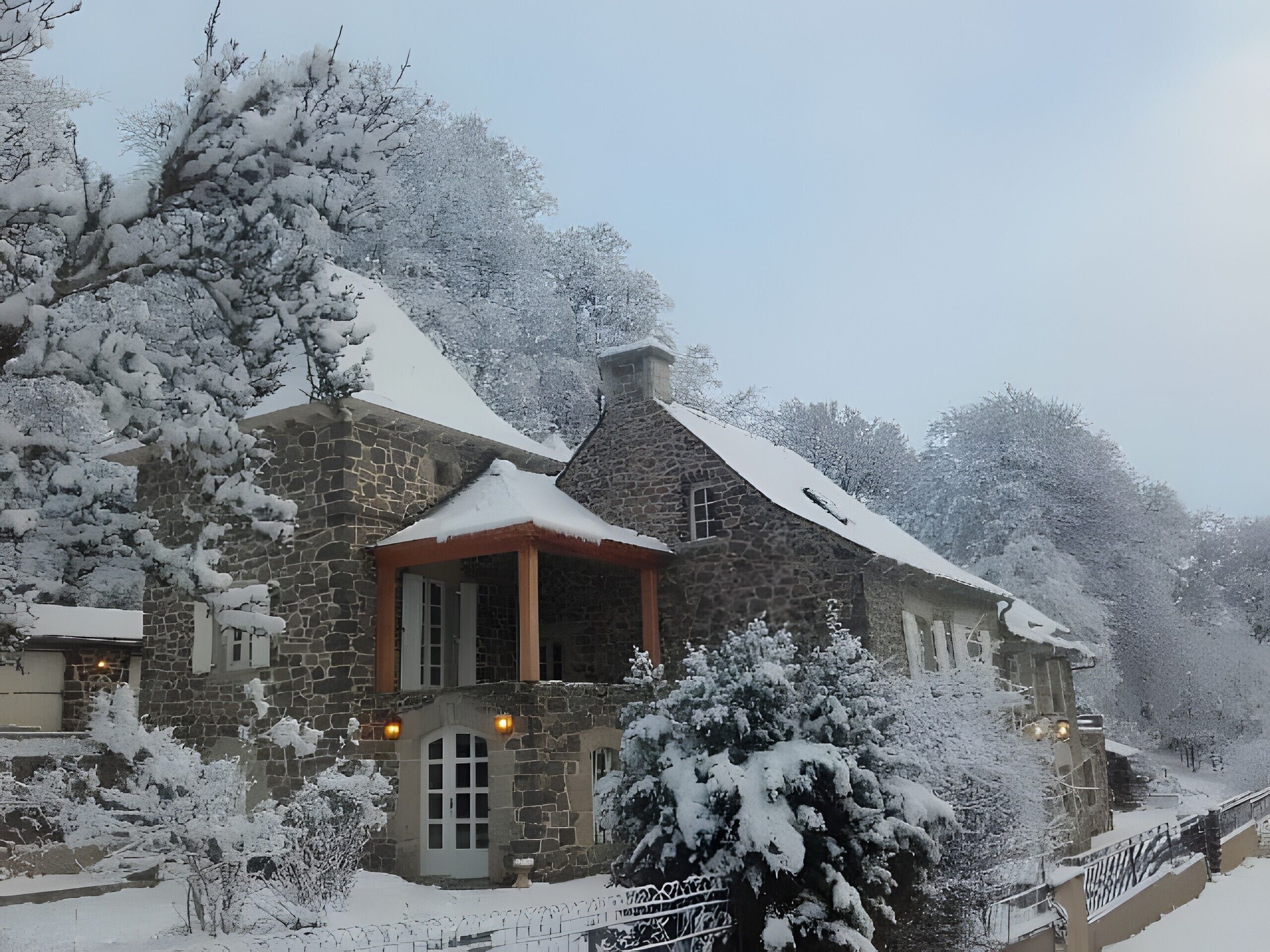 Un bâtiment en pierre, avec un toit recouvert de neige et un petit porche.