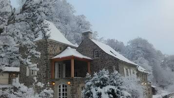 Un bâtiment en pierre, avec un toit recouvert de neige et un petit porche.