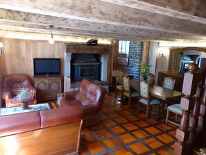 A cozy living room with a fireplace, leather furniture, and a dining area.