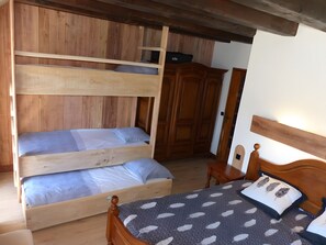A wooden bunk bed with two levels, a wooden wardrobe, and a bedside table with a lamp. - Holiday Home 'La Villa Des Papillons' with Mountain View, Private Terrace and Wi-Fi (Laguiole)