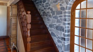 Una escalera de madera con un muro de piedra y una puerta de vidrio esmerilado.