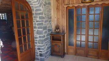 Una stanza con parete in pietra, porta in legno e una piccola credenza in legno con un orsacchiotto sopra.