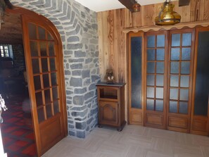 A room with a stone wall, wooden door, and a small wooden cabinet with a teddy bear on top.