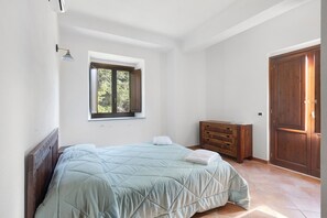 Un dormitorio con cama, cómoda, ventana y puerta.