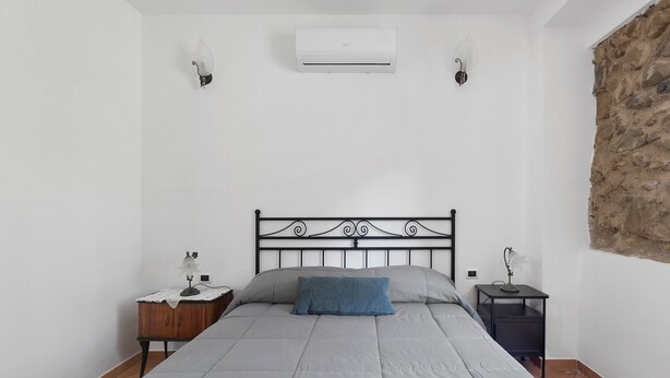 Een slaapkamer met een bed, twee nachtkastjes, een airconditioning en een wandlamp.
