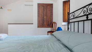 Une chambre à coucher avec un lit, une armoire en bois, une chaise et une fenêtre.