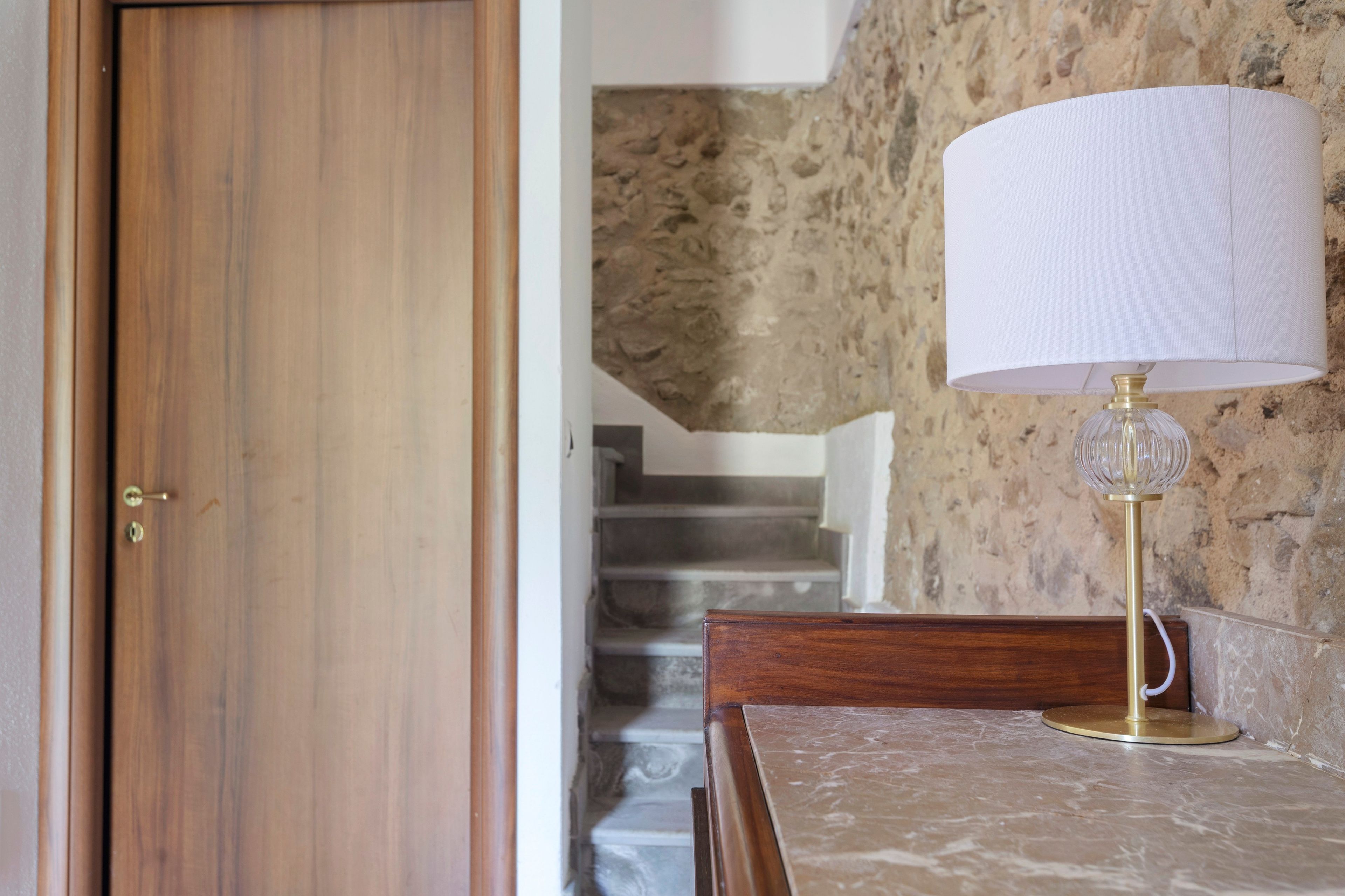 A wooden door, a marble table with a lamp, and a staircase against a textured wall.