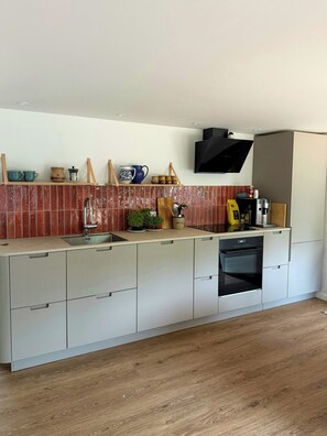 A modern kitchen with a built-in oven, a sink, and a microwave.