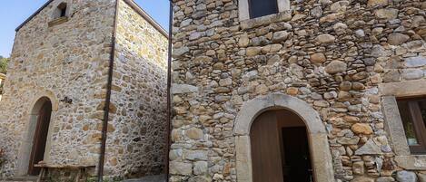 Un edificio de piedra con una ventana pequeña y un arco de entrada.