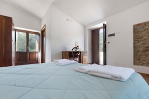 Una camera da letto con un letto grande, una cassettiera in legno e un muro in pietra.