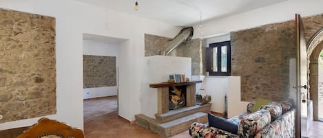 A room with a stone wall, a fireplace, a sofa, and a wooden staircase.