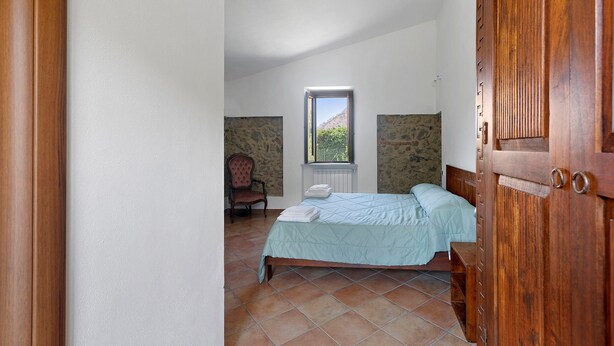 Een slaapkamer met een bed, een stoel, een raam en uitzicht op het landschap.