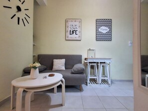 A modern living room with a grey sofa, a white coffee table, and two wall-mounted artworks. - A Cozy Urban Nest in Kolonaki (Athina)