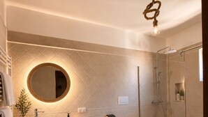 Ein modernes Badezimmer mit rundem Spiegel, einem Bidet, einer Toilette und einer Duschkabine.