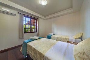 Une chambre d’hôtel avec deux lits, une fenêtre avec des rideaux, un appareil de climatisation et un luminaire au plafond.