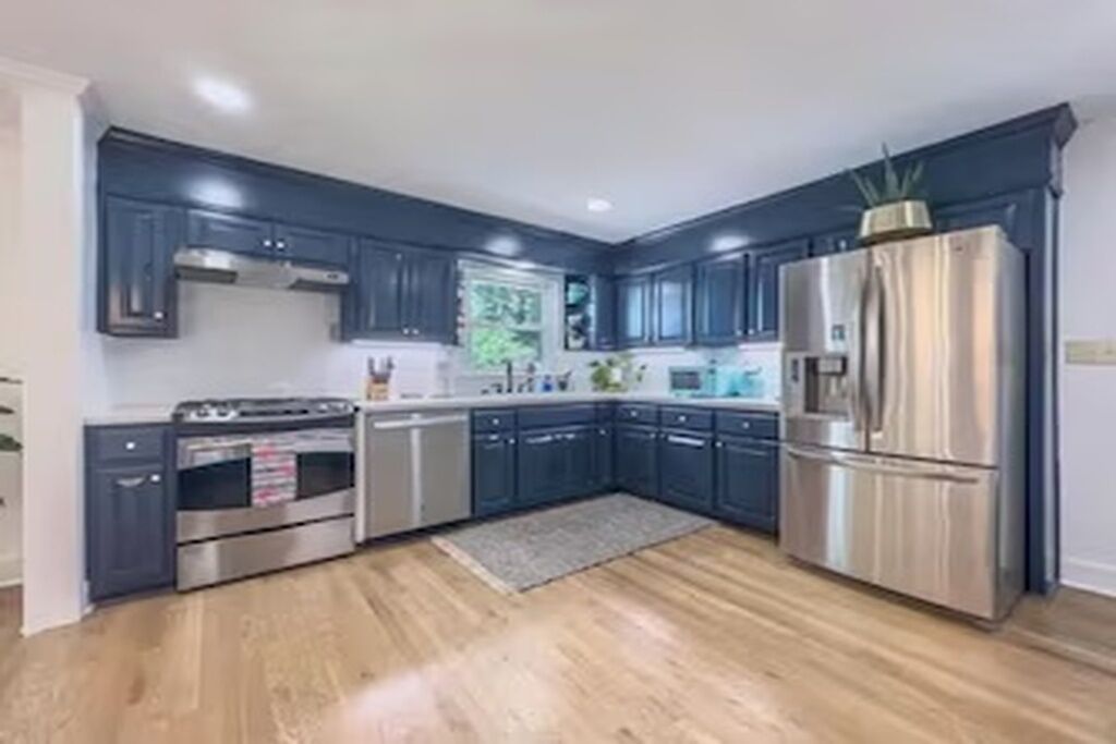 Una cocina moderna con armarios oscuros, electrodomésticos de acero inoxidable y piso de madera.