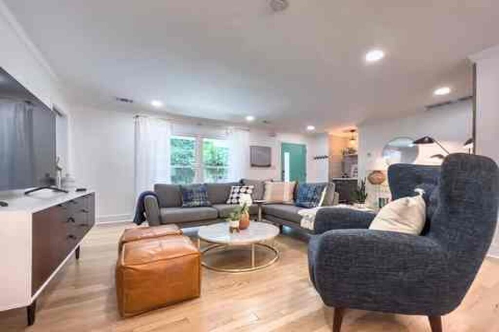 A modern living room with a sofa, armchair, ottoman, and coffee table.