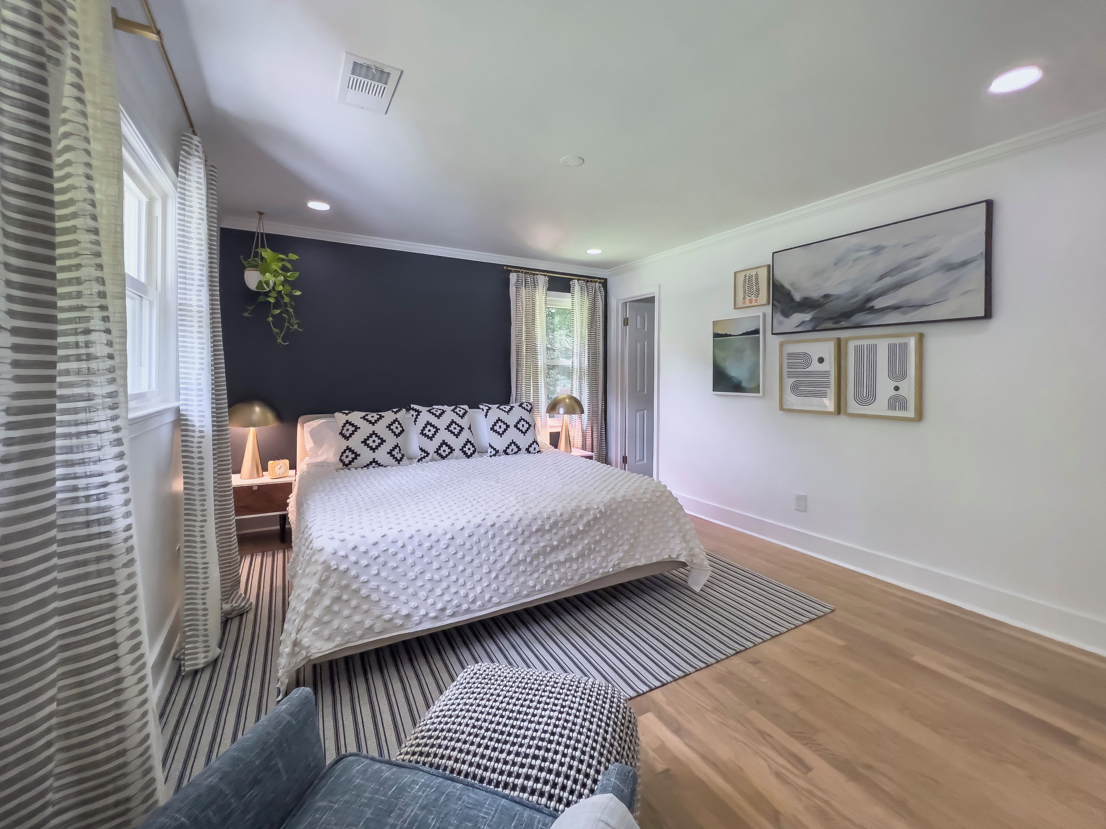 A modern bedroom with a bed, bedside tables, a lamp, and artwork on the wall.