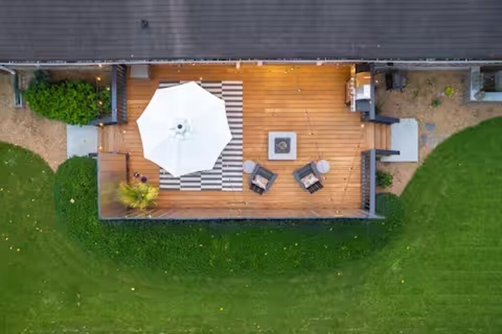 An aerial view of a deck with a large umbrella, seating, and a small garden area.